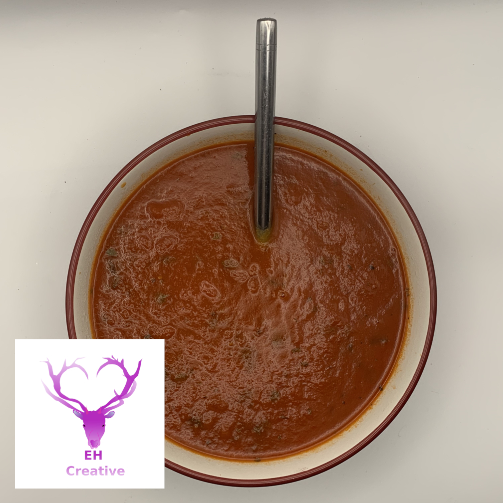 A bowl of tomato soup with spoon